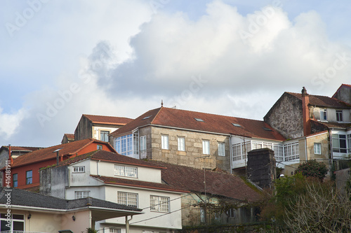 Stacked old houses with cloudy sky. granite stone house with tile roof. white houses and white aluminum windows. neighborhood of old houses.