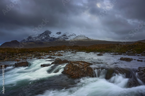 Long exposure of water over rocks and small waterfall on the River Sligachan on the Isle of Skye Scotland with the Cuillin mountain range in the distance with snow in winter  Isle of Skye  Scotland