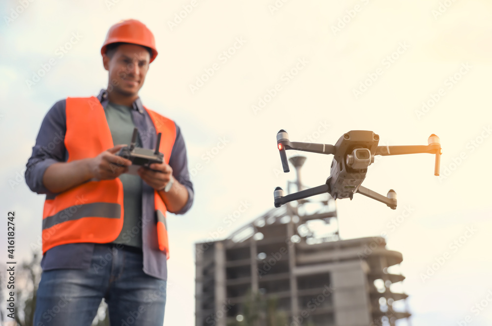 Builder operating drone with remote control at construction site. Aerial photography
