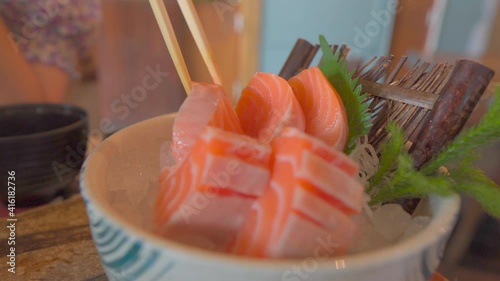 Salmon sashimi eating by a chopsticks from ice bowl