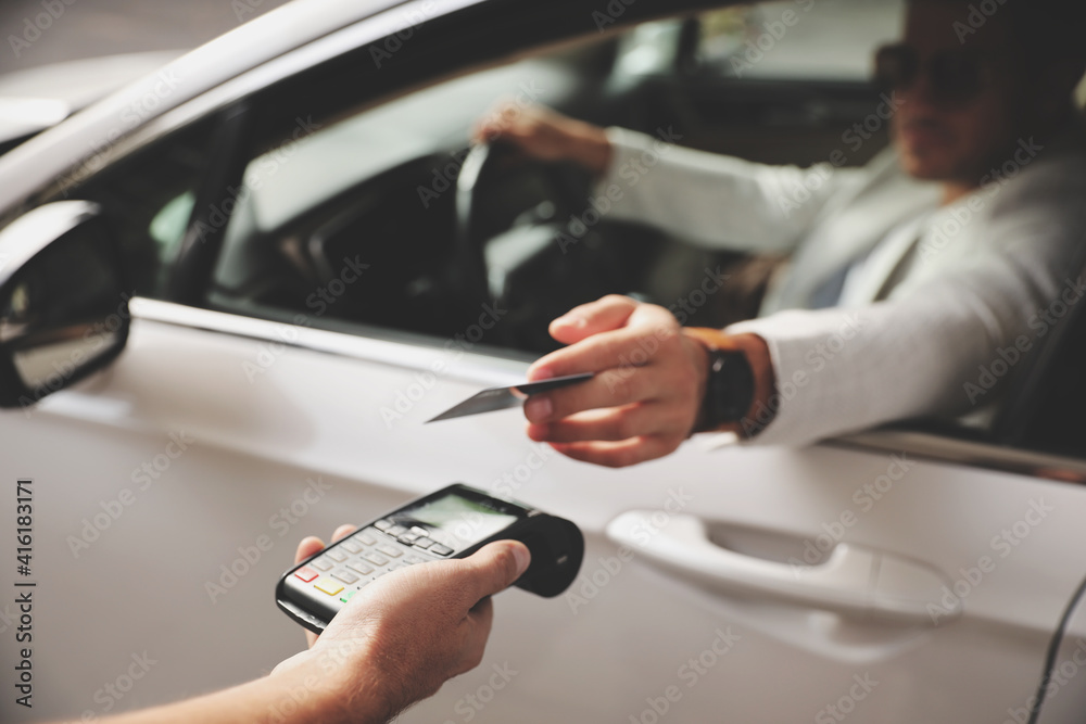 Man sitting in car and paying with credit card at gas station, focus on hand Man sitting in car and paying with credit card at gas station, focus on hand