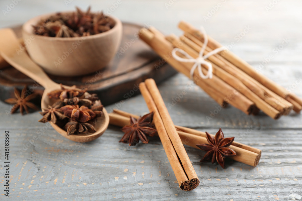 Fototapeta premium Aromatic cinnamon sticks and anise on grey wooden table
