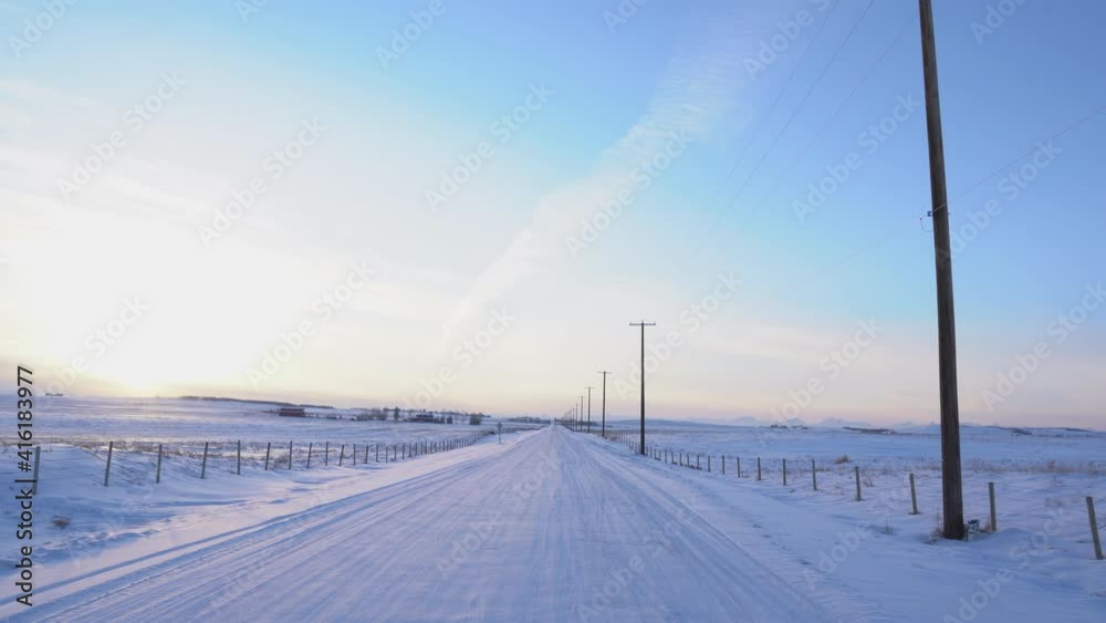 A rural township with power lines and power poles along a snow covered road in North America. A rural township with power lines and power poles along a snow covered road in North America.