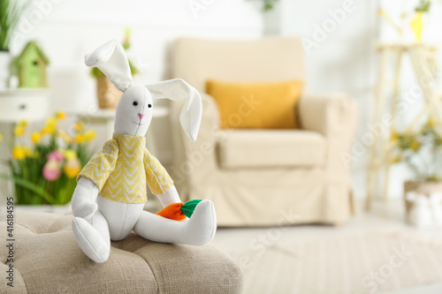 Cute toy rabbit on bench indoors. Easter photo zone