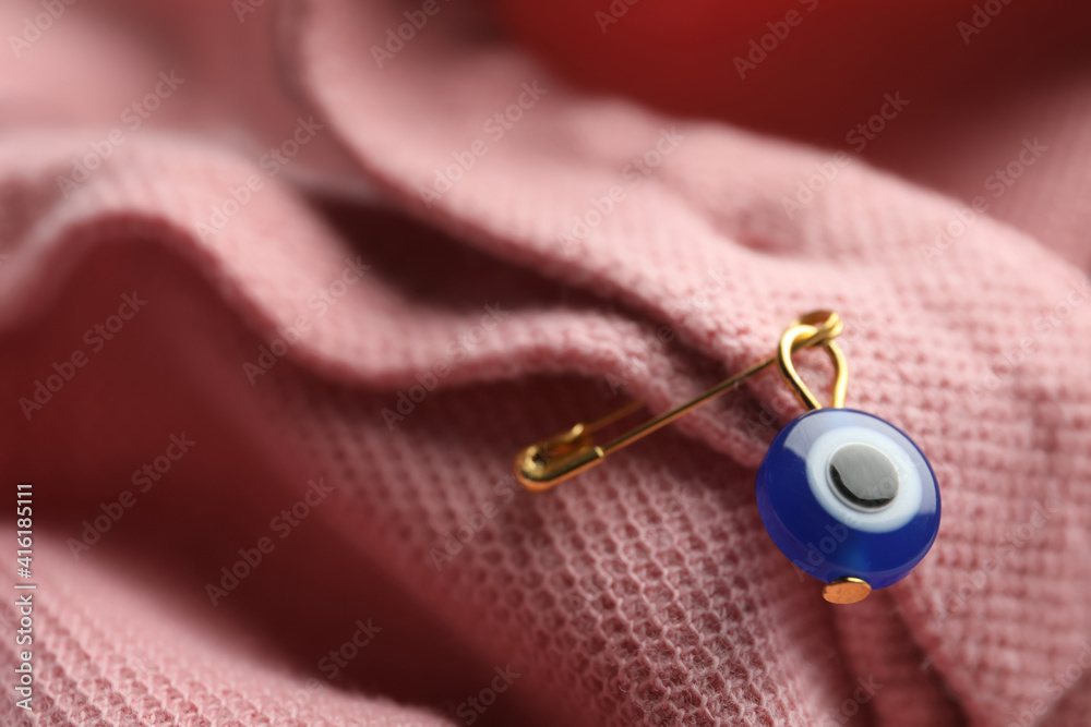 Naklejka premium Evil eye safety pin on clothing, closeup