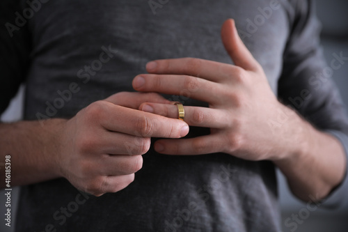 Bild auf Leinwand Man taking off wedding ring on blurred background, closeup
