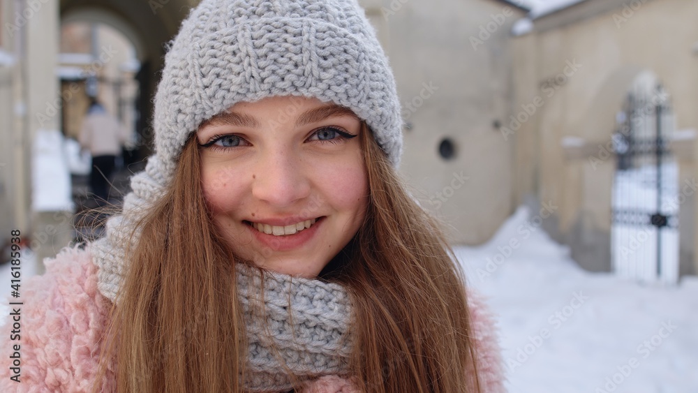 Portrait of Caucasian pretty happy girl with smile on face posing on street in city. Close-up of cheerful young woman smiling to camera while standing outdoors in winter. Positive emotions concept Portrait of Caucasian pretty happy girl with smile on face posing on street in city. Close-up of cheerful young woman smiling to camera while standing outdoors in winter. Positive emotions concept