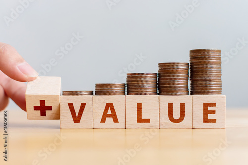 Wooden cube block with word VALEU and money coins stack step up growth on wood table photo