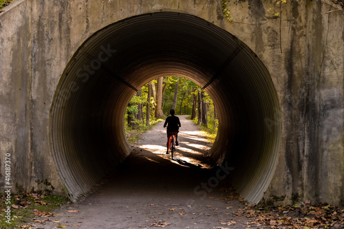 Принти на полотні Woman Bikes Through Tunnel on Towpath