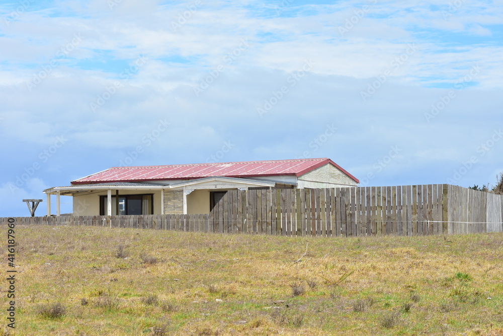 Rural wooden house with sheet metal roof and slate fence placed in dry ...