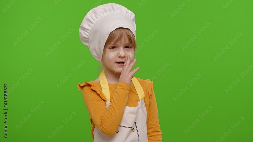 Child girl kid dressed as professional cook chef holding finger on her lips on chroma key background. Gesture of shhh, hush, secret, silence. Nutrition, cooking school, education, food. Fun and humor Child girl kid dressed as professional cook chef holding finger on her lips on chroma key background. Gesture of shhh, hush, secret, silence. Nutrition, cooking school, education, food. Fun and humor