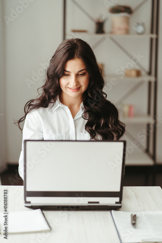 Woman working at home with laptop and documents