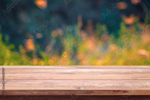 Empty wood table with bokeh yellow flowers in garden background.