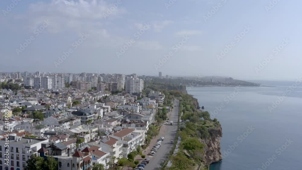 Drone video of the coastline of the city on the Mediterranean Sea. Houses and streets with high-rise buildings stand on the rocks washed by the waves of the sea. Aerial view Antalya Turkey. Drone video of the coastline of the city on the Mediterranean Sea. Houses and streets with high-rise buildings stand on the rocks washed by the waves of the sea. Aerial view Antalya Turkey.