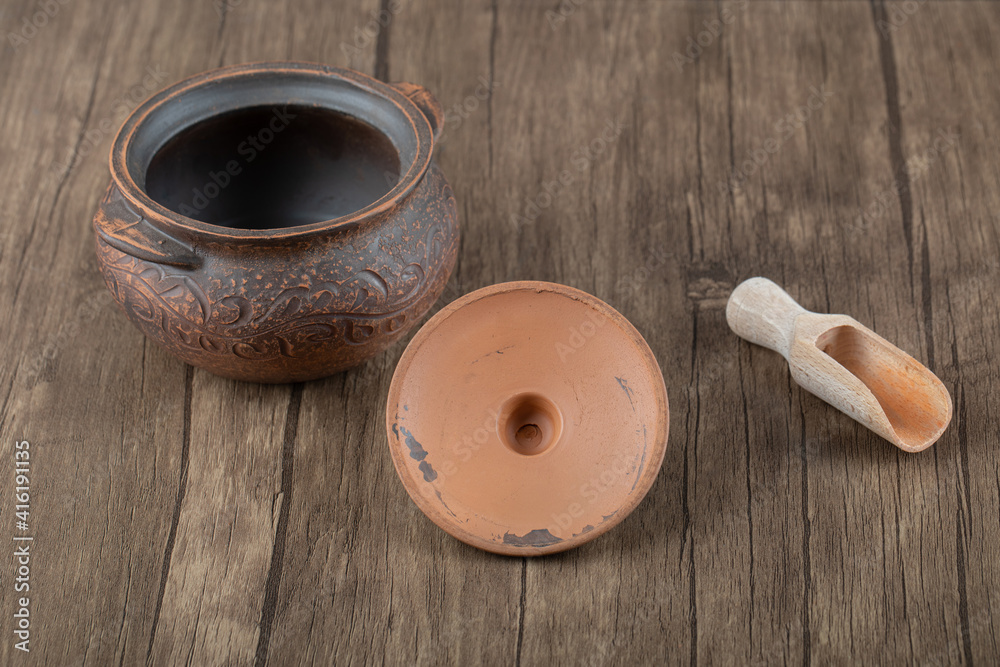 Ancient pot with a wooden spoon on a wooden table