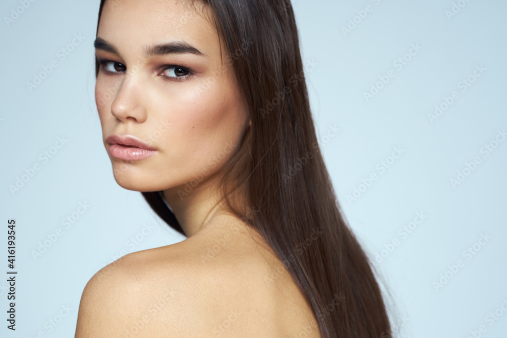 Woman with naked shoulders long hair clean skin cropped view blue background Woman with naked shoulders long hair clean skin cropped view blue background