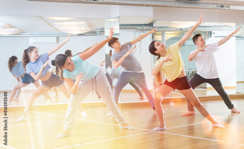 Obraz premium Positive smiling slim teenagers dancing hip hop in dance class