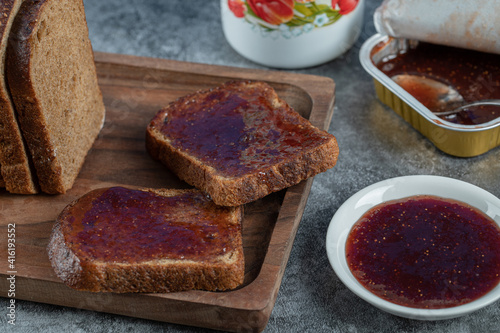 Strawberry jam with slice of brown bread and cup of tea