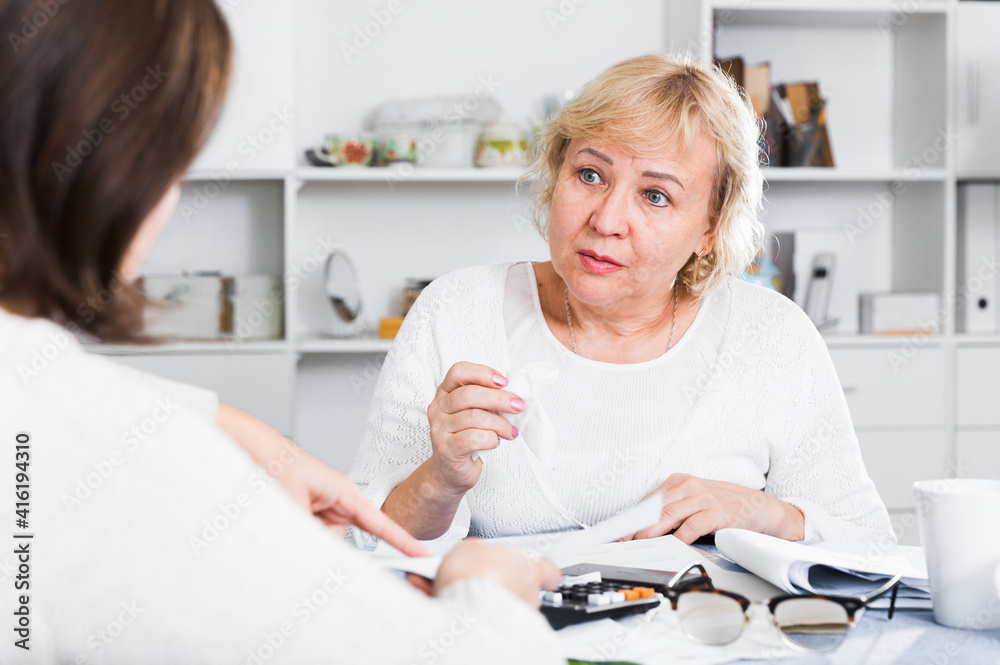 Obraz premium Mature woman consults with a financial adviser for the proper conduct of home accounting