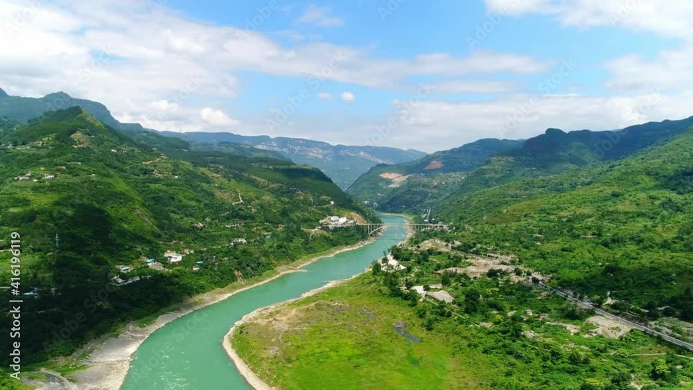 Aerial shot of green mountains and a turquoise river between valleys in China Aerial shot of green mountains and a turquoise river between valleys in China