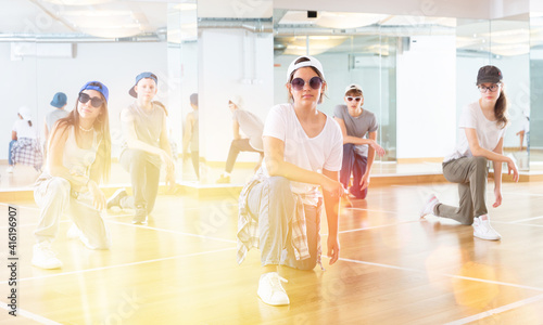 Cheerful teenagers hip hop dancers kneeling on floor during group dance workout