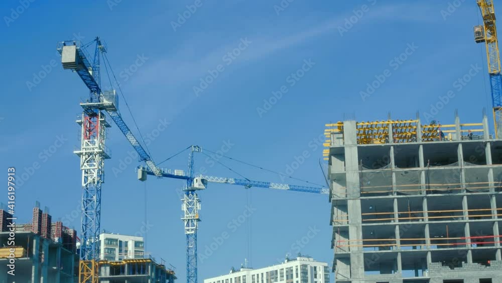 Two white high-rise buildings can be seen in the distance. Other high-rise buildings are being built near them. One of them employs workers. There are cranes near the other buildings. One is working. Two white high-rise buildings can be seen in the distance. Other high-rise buildings are being built near them. One of them employs workers. There are cranes near the other buildings. One is working.