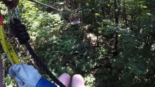 Person in Harness Riding Zip Line through Georgia Forest Trees, POV photo