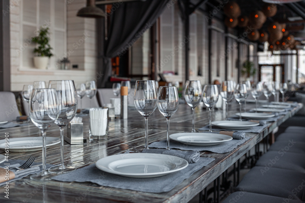 Modern veranda restaurant interior, banquet setting, glasses, plates