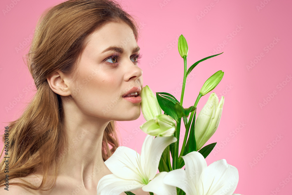 Portrait of a beautiful woman with white flowers in her hands on a pink background Copy Space cropped view