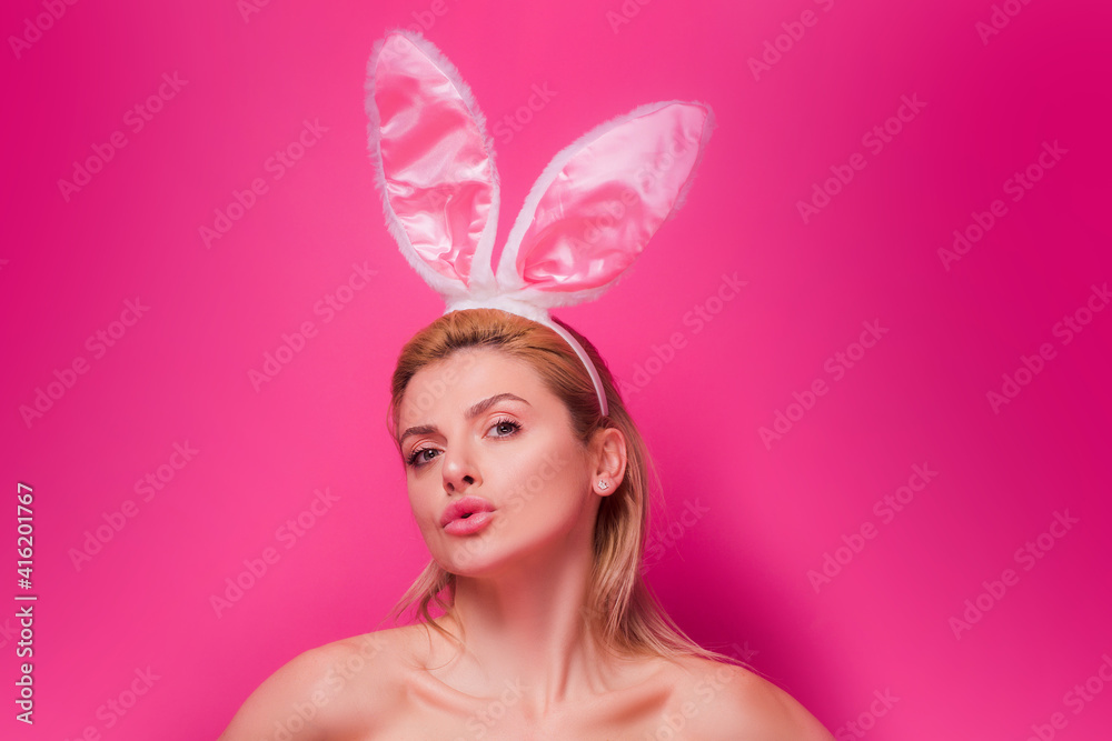 Lovely beautiful sensual young woman posing in pink bunny ears. Studio shot of easter girl isolated on pink.