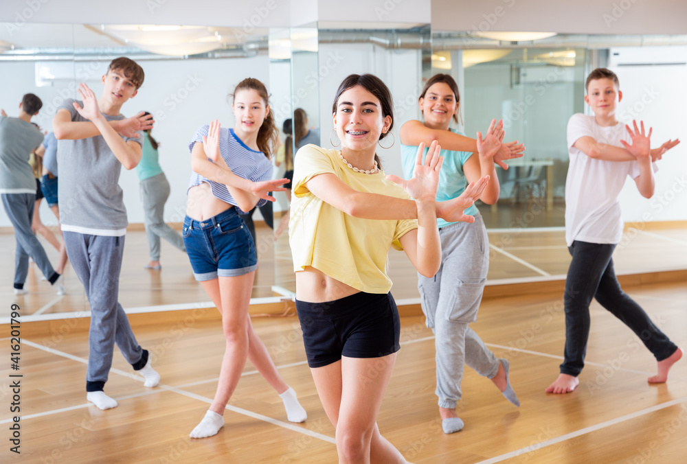 Teenagers in dance hall studying new movements, smiling and having fun