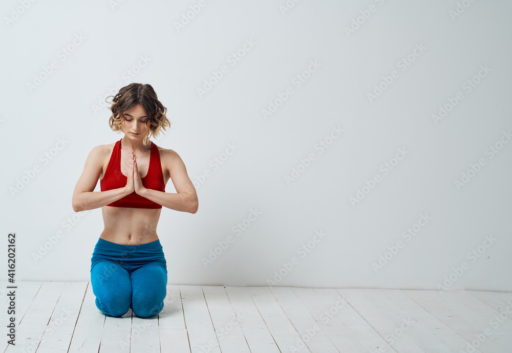 Woman Practicing Yoga In A Bright Room And Blue Leggings Red T-shirt Woman Practicing Yoga In A Bright Room And Blue Leggings Red T-shirt