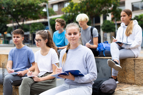 Open air lecture. Students record lecture while sitting on a stone street parapet