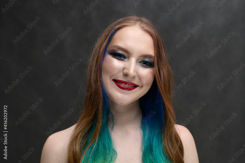 Fototapeta premium portrait of a girl with dyed hair smiling on a gray background