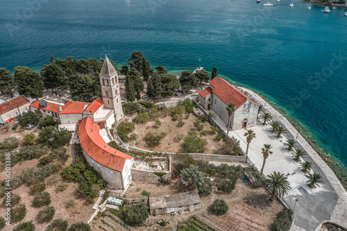 Aerial drone shot of St. Jeronima church with stone tower on Vis Island port in Croatia summer