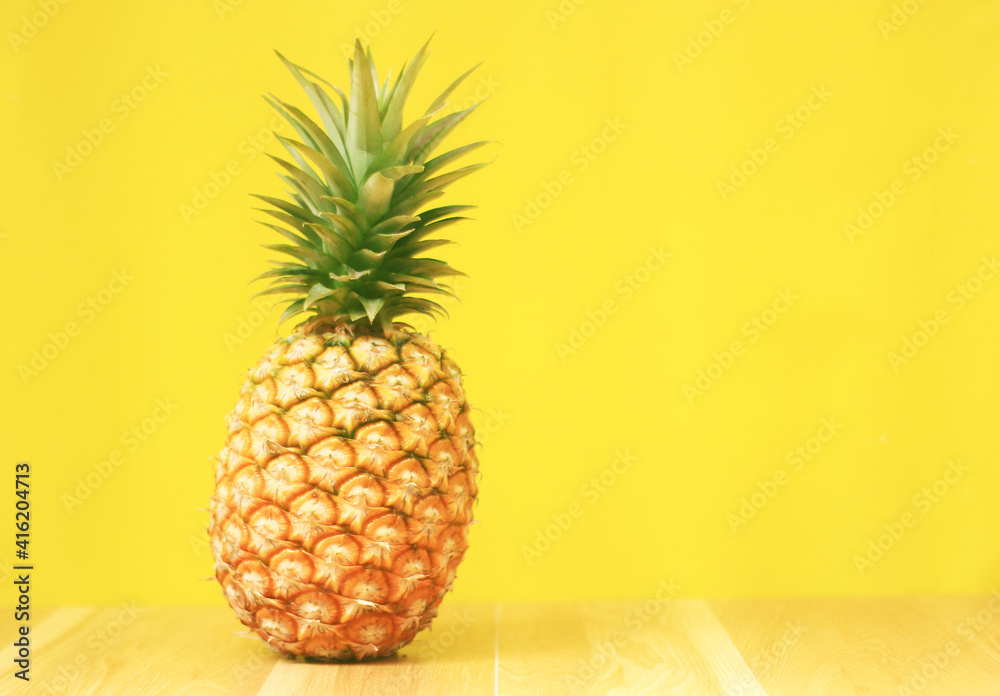 Ripe pineapple on a yellow wooden background Ripe pineapple on a yellow wooden background