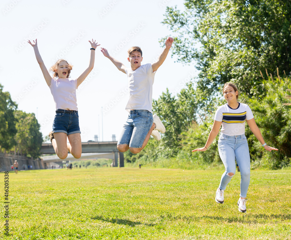 Obraz premium Happy teenagers jumping on the green lawn on spring