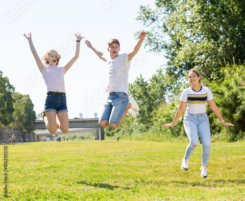 Happy teenagers jumping on the green lawn on spring