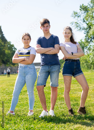 Fototapeta Naklejka Na Ścianę i Meble -  Teenagers with arms crossed are standing on the spring lawn of the park