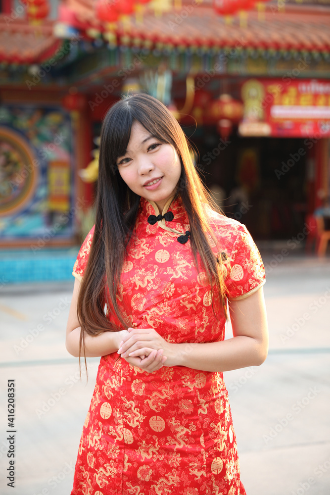 Naklejka premium beauty woman wear red cheongsam looking and smile in chinese new year