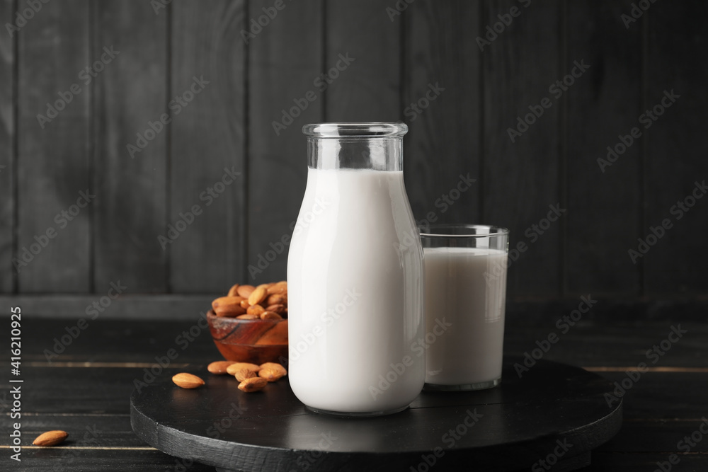 Bottle and glass of tasty almond milk on dark background Bottle and glass of tasty almond milk on dark background