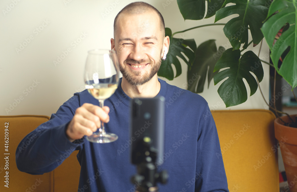 Online party concept. The man with a glass of white wine is video calling by smartphone the girl from his apartment. Online dating, virtual meeting, internet dates. Selective focus Online party concept. The man with a glass of white wine is video calling by smartphone the girl from his apartment. Online dating, virtual meeting, internet dates. Selective focus