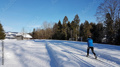 Langläuferin auf einer menschenleeren Langlaufloipe in schöner Winterlandschaft