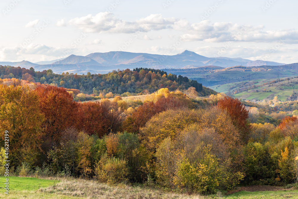 Autumn mountain landscape - yellowed and reddened autumn trees combined with green needles and blue skies. Colorful autumn landscape scene in the Ukrainian Carpathians. Panoramic view. Autumn mountain landscape - yellowed and reddened autumn trees combined with green needles and blue skies. Colorful autumn landscape scene in the Ukrainian Carpathians. Panoramic view.