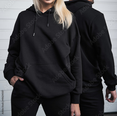 young bearded man and blonde girl is standing in plain hoodie for logo printing. Clothing mockup for hoodie. Autumn youngsters streetwear photo