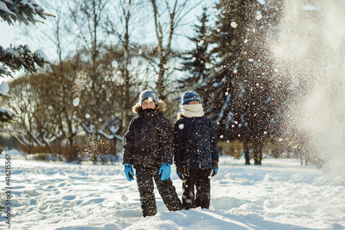 Obraz na plátně Cute caucasian boys standing under the snow squall in a snowy winter park in Russia