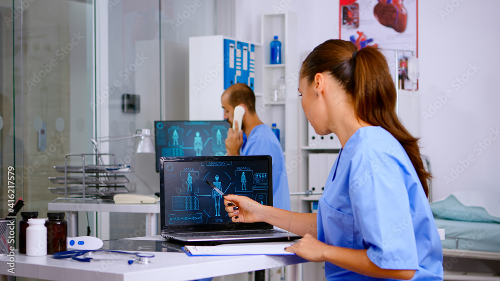 Obraz premium Student medical practitioner analysing human body digital scan, holding radiography sitting in hospital. Radiologist in medicine uniform looking at x-ray, examination, bone, practitioner, diagnosis.