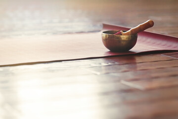 Fototapete Yogaschule Eine Klangschale steht auf einer Yogamatte auf einem Holzboden mit Kopierraum. Klangtherapie und Entspannungskonzept.  © Roman