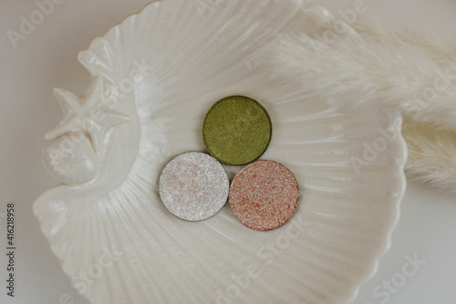 Beautiful bright eye shadows on white plate in the form of a shell