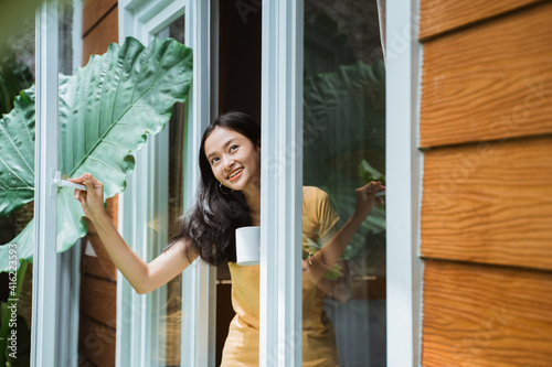 beautiful asian woman drinking coffee in the morning by the window. view from outside.